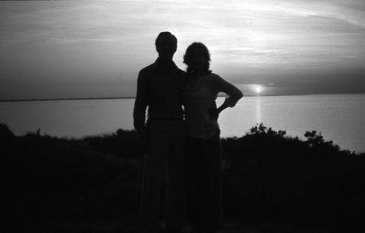 black and white silhouette of man and woman at sunset by the ocean